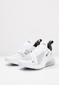 Weiße Nike Air Max 270 Sneaker mit schwarzen Akzenten, Obermaterial aus Mesh, durchlöchertem Design, gepolstertem Kragen und transparenter Luftpolstersohle.