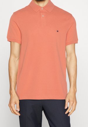 Polo shirt corallo realizzato in cotone, con colletto classico, tre bottoni e un piccolo logo sul petto. Maniche corte e finitura testurizzata.