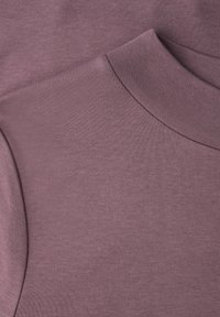 Gros plan sur un tissu tricoté mauve lisse avec un col montant et des détails de couture subtils.