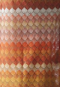 Tissu en dentelle présentant un dégradé de couleurs allant du rouge profond à l'orange, puis au jaune, avec des motifs complexes de diamants et de feuilles crocheted dans un fil fin.