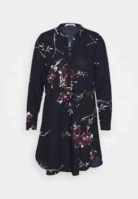 Schwarzes Blumenkleid mit langen Ärmeln, Knopfleiste, Kragen und Kordelzug in der Taille. Der Stoff ist mit roten und weißen Blumenmustern versehen.
