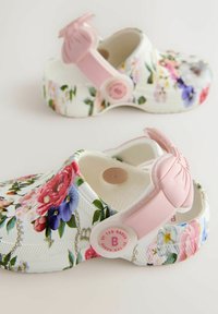 Kleitvõttega puulusikad valges toonis, millel on roosa rihm ja lipsudetail. Valmistatud kergest materjalist, tekstureeritud tallaga, mis tagab haarde.