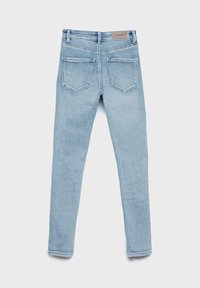 Jean en denim bleu clair vu de dos avec deux poches et une petite étiquette de marque à la taille, posé à plat sur un fond blanc.