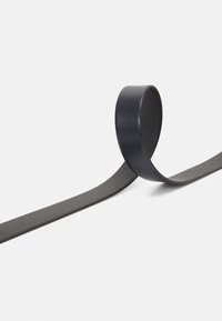 Čierny gumový opasok s hladkým, zaobleným povrchom, s plochým popruhom vystupujúcim z navinutého úseku, minimalistic design.