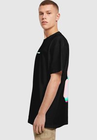 Sort bomulds T-shirt med korte ærmer, med et flerfarvet grafikdesign på bagsiden, rund hals og afslappet pasform.