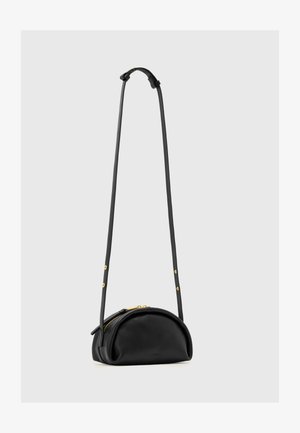 Zwarte halfcirkelvormige leren crossbodytas met lange verstelbare band en gouden ritsaccenten, hangend tegen een effen lichte achtergrond.