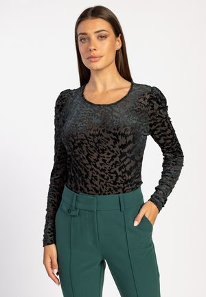 Zwarte lange mouwen top met een textuur van dierenprint, met een ronde hals en gathered mouwaccenten, gecombineerd met hoog-gepunte groene broek.
