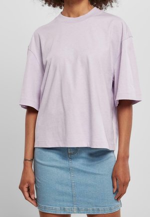 Liliowa oversize koszulka z krótkimi rękawami, okrągłym dekoltem i miękką teksturą, zestawiona z dopasowaną mini spódnicą jeansową dla kontrastu.