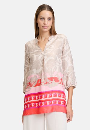 Lichtgewicht, gevoerd blouse in beige met roze en rode accenten, met een v-hals, driekwartmouwen en een vloeiende pasvorm.