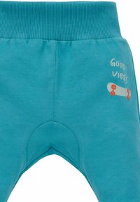 Türkise Baumwollhosen mit einem gerippten Bund, ausgestattet mit einem bedruckten Skateboard-Motiv und dem Text "Good Vibes" an der Seite.