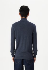 Marineblauer Pullover mit geripptem Kragen und Bündchen, langen Ärmeln und einer glatten Textur. Die Rückansicht zeigt ein minimalistisches Design.