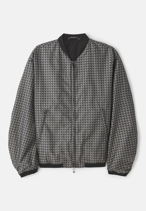 Chaqueta bomber texturizada en gris con un patrón geométrico. Presenta un cierre frontal con cremallera, cuello negro y puños y dobladillo elásticos.