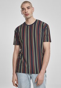 Rövid ujjú, tengerészkék póló függőleges piros, sárga és zöld csíkokkal. Pamutból készült, kerek nyakkivágással és laza szabással.