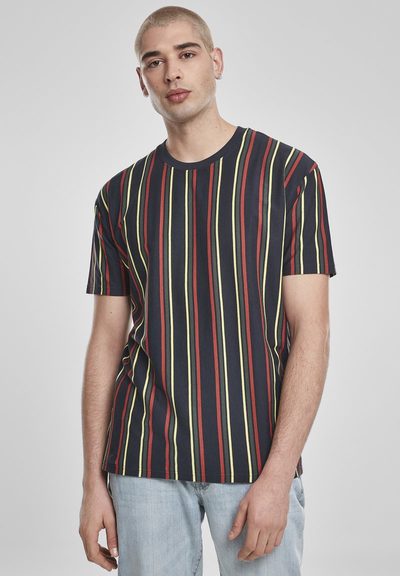 Rövid ujjú, tengerészkék póló függőleges piros, sárga és zöld csíkokkal. Pamutból készült, kerek nyakkivágással és laza szabással.