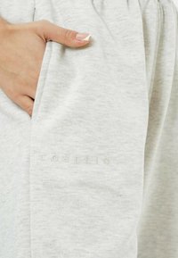 Helle graue Jogginghosen aus weichem, strukturiertem Stoff. Mit gesticktem Logo-Detail und seitlichen Taschen. Elastischer Bund für hohen Tragekomfort.