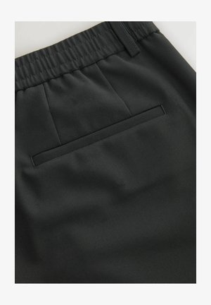 Mustadest tekstuuriga kangast püksid, millel on elastne vöökoht, ees voldid ja taga üks kott.