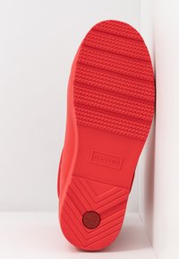 Semelle de botte en caoutchouc rouge avec un motif de grip texturé, avec le nom de la marque "HUNTER" en relief et le logo. Conçue pour la durabilité et la résistance à l'eau.