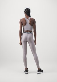 Ljusgrå sport-bh och leggings med svart midjeresår; slät textur; racerback-design; ihopparat med svarta träningsskor.