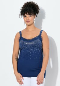 Navyblauwe tanktop van zachte stof, met kantafwerking en verspreide rhinestones ter versiering, aansluitende silhouette met verstelbare banden.