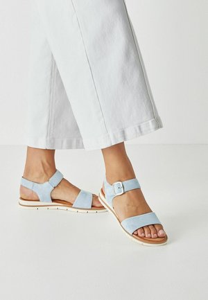 Hellblaue Wildleder-Sandalen mit breiten Riemen, verstellbarer Fesselriemen-Schließe und weißer Gummisohle. Strukturierte Oberfläche und offenes Zehendesign.