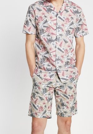 Camisa de manga corta floral y pantalones cortos a juego en beige claro con patrones botánicos en rosa, verde y gris. Tejido ligero, ajuste casual.
