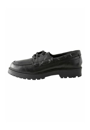 Black leather boat shoe with a rounded toe, low profile, and textured sole. Features eyelets for laces and stitched detailing along the sides.