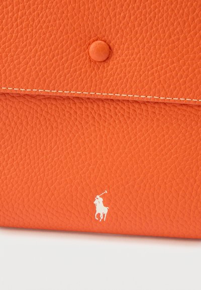 Oransje teksturert lær clutch med hvit sydd kant, knappelukking med trykknapp og hvit polo-spillerlogo nær bunnen i midten.