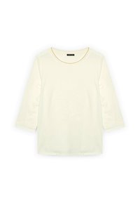 Haut en coton couleur crème à manches trois quarts, présentant un motif floral texturé au centre et des accents décoratifs sur les manches.