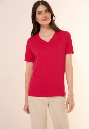 T-shirt à col en V à manches courtes de couleur rouge vif, fabriqué à partir d'un tissu doux avec une texture lisse. Il présente une coupe décontractée et un design minimaliste.