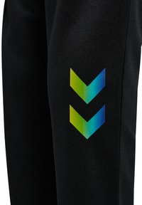 Czarne spodnie sportowe wykonane z teksturowanego materiału. Na lewej nogawce znajduje się żywy, gradientowy wzór w kształcie szewrona w kolorach zielonym i niebieskim.