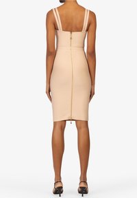 Nudefarbenes Bodycon-Kleid mit dünnen, verstellbaren Trägern, einer taillierten Silhouette und einem goldenen Reißverschlussdetail auf der Rückseite. Glatte Textur, knielang.
