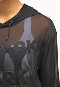 Sudadera negra y transparente con una superposición gris que presenta grandes letras "MY PARK". Tiene una capucha con cordón y una textura de tela suave.