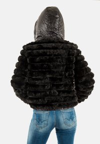 Zwarte, nepbontjas met een capuchon, gekenmerkt door een getextureerd, geribbeld ontwerp en een cropped silhouet. Draag het over lichtblauwe jeans.