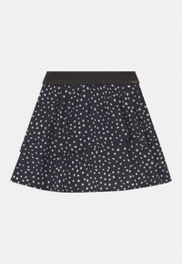 Jupe superposée bleu marine avec un motif de points blancs irréguliers et une ceinture sombre unie, posée à plat sur un fond blanc.