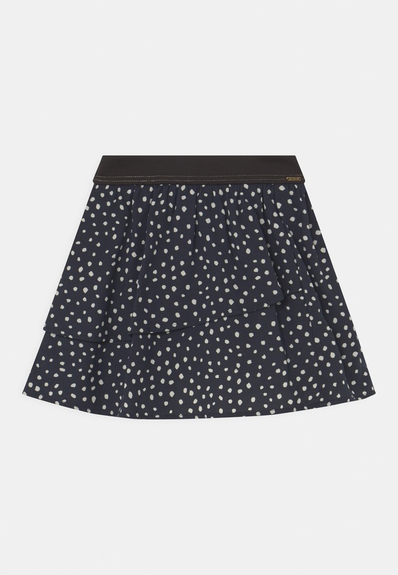 Jupe superposée bleu marine avec un motif de points blancs irréguliers et une ceinture sombre unie, posée à plat sur un fond blanc.