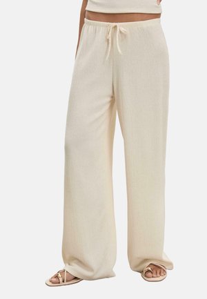 Pantalons larges de couleur crème en tissu texturé, dotés d'une taille élastique avec cordon de serrage et d'une coupe décontractée.