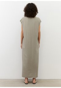 Długa, bezrękawnikowa sukienka z jasnoszarego materiału. Posiada luźny krój i prostą sylwetkę, bez widocznych elementów metalowych ani wzorów.