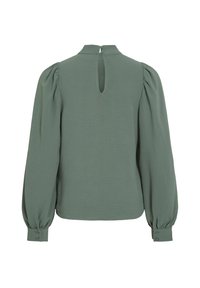 Blouse verte à manches longues présentant un col haut, un détail en forme de trou de serrure au dos et des manches ballon doucement froncées. Fabriquée en un tissu texturé.