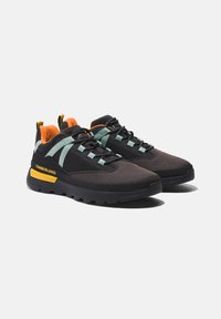 Scarpe da ginnastica nere e grigie scure realizzate in materiale a rete, con accenti verdi e rivestimenti arancioni. Presentano una suola spessa nera e marchiatura gialla.
