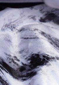 Abstrakcyjna tkanina o fakturowej powierzchni, z monochromatycznym wzorem czarno-białych pociągnięć pędzla. Gładkie i lekko błyszczące wykończenie.