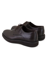 Chaussures en cuir marron avec une finition lisse, bout rond, système de laçage et semelle épaisse en caoutchouc pour une bonne adhérence. La vue arrière montre des accents minimaux.