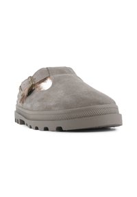 Chaussure slip-on en cuir suédé gris avec un bout fermé, des côtés ouverts et une sangle décorative. Présente une semelle en caoutchouc texturé avec des rainures de traction.