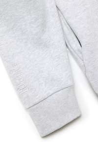 Felpa grigia con lavorazione a maglia testurizzata, dotata di chiusura con zip sul lato e discreti dettagli ricamati sul polsino.