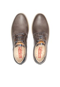 Chaussures en cuir perforé marron avec un bout rond, un laçage à l'avant et une semelle en caoutchouc contrastante. Comprend un intérieur à motifs et des détails de marque.