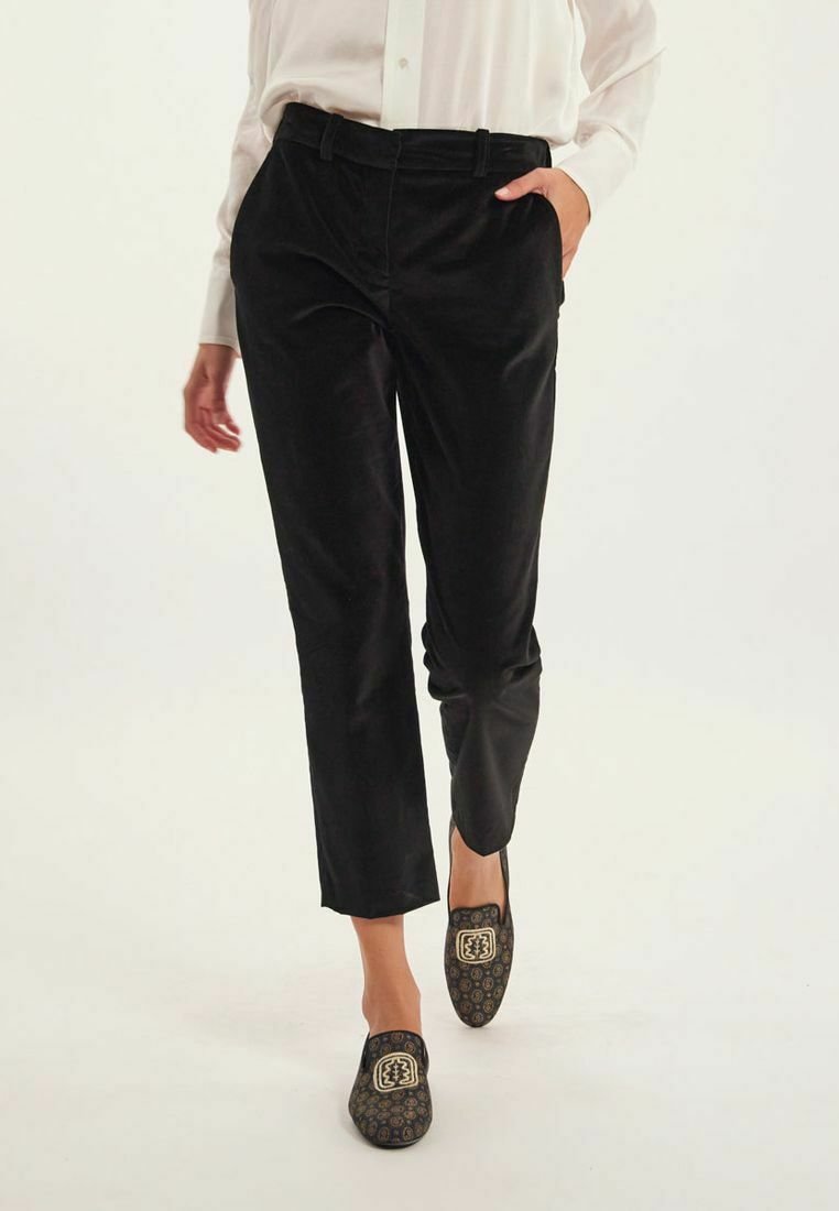 Pantalon en corduroy noir avec une coupe slim, doté de poches latérales peu profondes et d'une texture lisse, associé à des mocassins noirs à motif.
