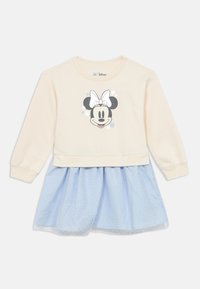 Kremna majica z dolgimi rokavi z grafiko Minnie Mouse, kombinirana s svetlo modro krilo s pikami. Material je mehak; dizajn ima plastni videz.