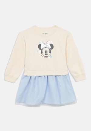 Cream long-sleeve top with a Minnie Mouse graphic, paired with a light blue polka-dot skirt. Fabric is soft; design features a layered look.