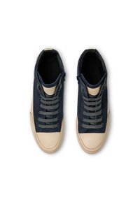 Navy high-top sneakers with a cream rubber toe cap, grey laces, and a zippered closure on the side, featuring textured accents.
