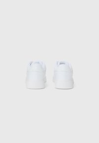 Hvite sneakers med en glatt læroverdel, polstret krage, gummisåle og minimal detaljering. Designet fremhever enkelhet og komfort.