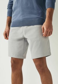 Shorts grii deschis cu față plată, buzunare laterale și margini drepte. Asortați cu un pulover albastru cu manșete și margine cu nervuri.